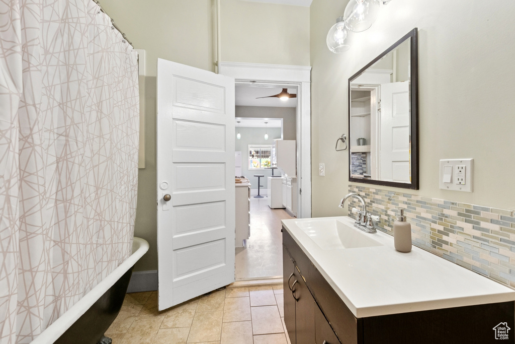 Full bath with tasteful backsplash, vanity, and tile patterned flooring