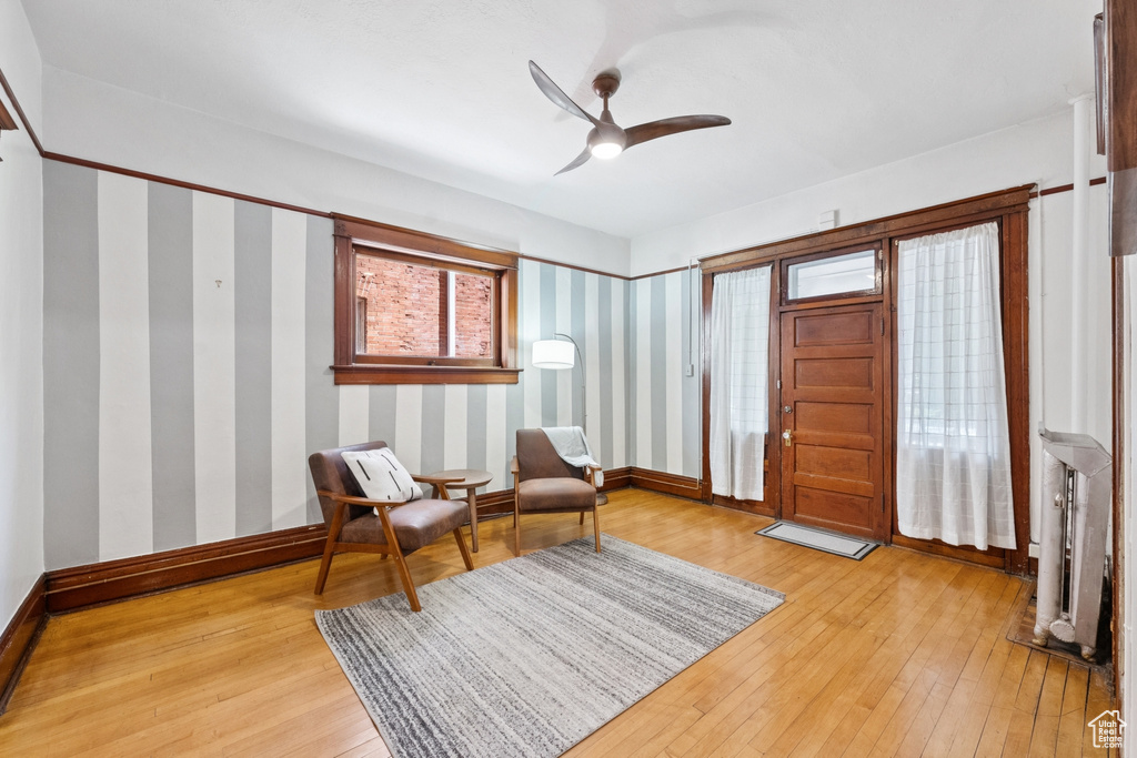Sitting room featuring light wood-style floors, ceiling fan, and wallpapered walls