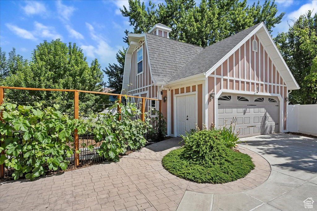 View of front facade featuring roof with shingles, concrete driveway, board and batten siding, and an attached garage
