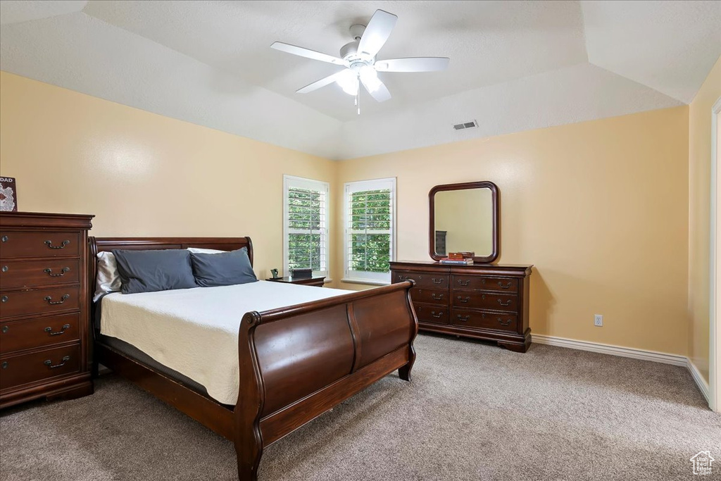 Bedroom with light colored carpet, vaulted ceiling, and a ceiling fan