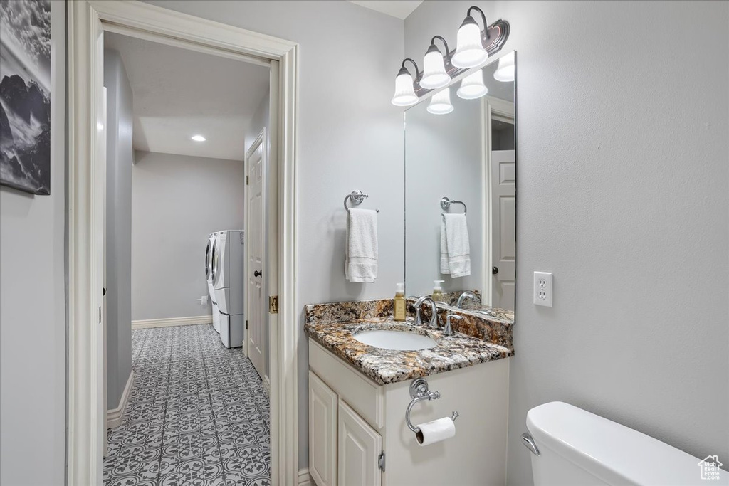 Bathroom featuring vanity, tile patterned floors, washing machine and clothes dryer, and recessed lighting
