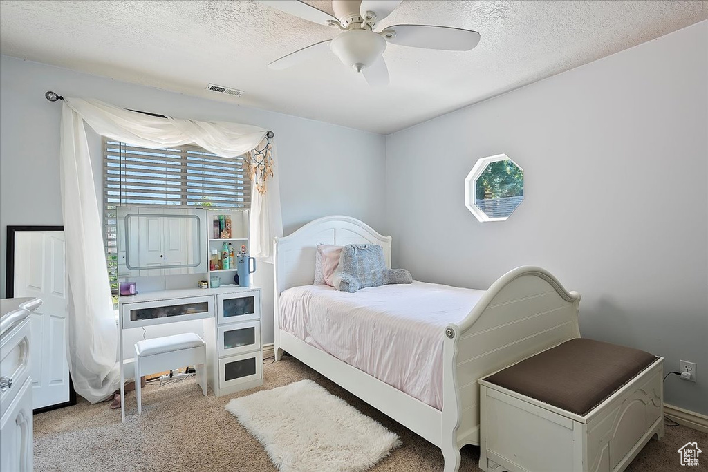 Bedroom with carpet flooring, a ceiling fan, and a textured ceiling