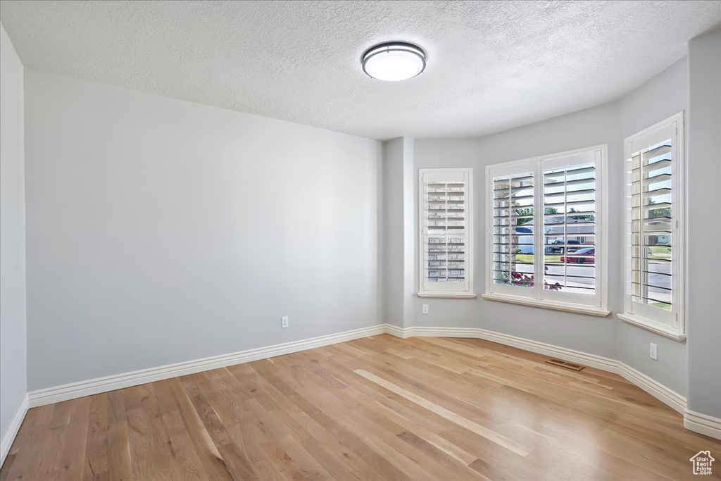 Unfurnished room featuring light wood finished floors and a textured ceiling