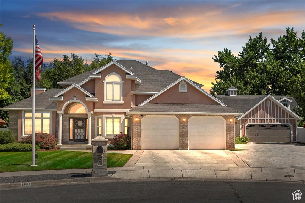 View of front of property featuring a garage, concrete driveway, stucco siding, and brick siding