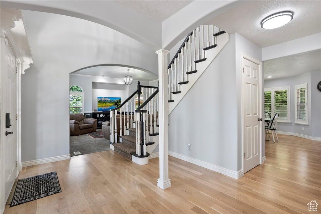 Entryway featuring light wood-style flooring, stairway, and arched walkways