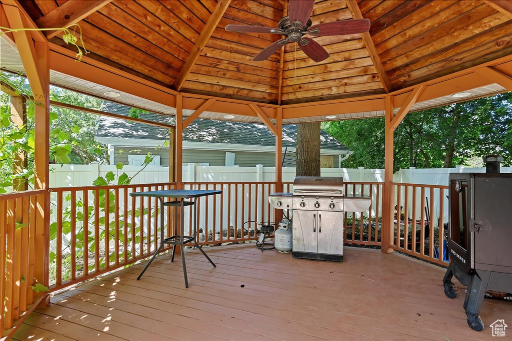 Wooden terrace featuring a ceiling fan, a gazebo, area for grilling, and a fenced backyard