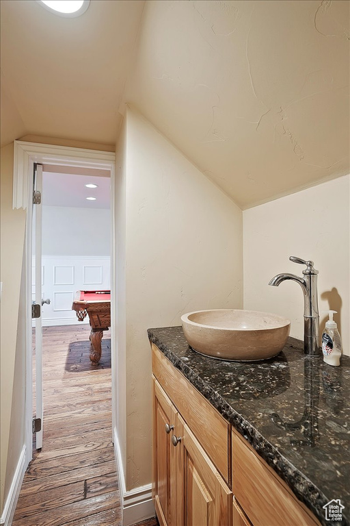 Bathroom with wood finished floors, pool table, vaulted ceiling, and vanity