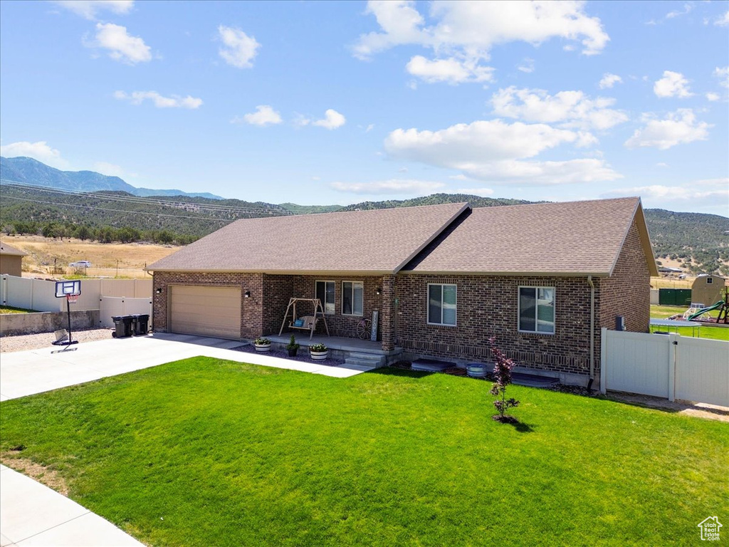 Single story home with brick siding, a mountain view, concrete driveway, and roof with shingles
