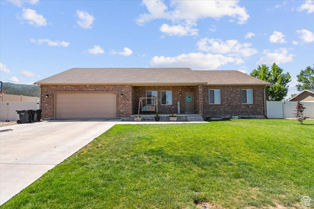 Ranch-style home featuring concrete driveway, a garage, brick siding, and roof with shingles
