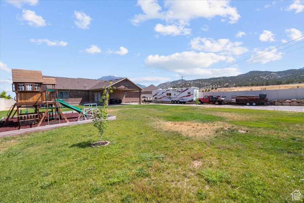 View of green lawn with a playground and a mountain view