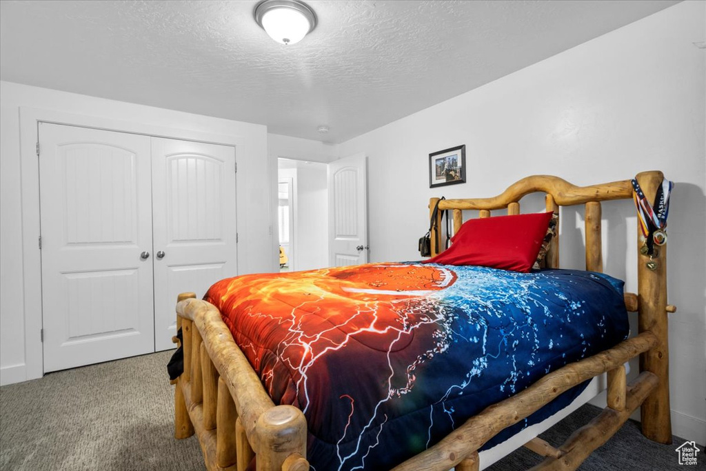 Carpeted bedroom featuring a closet and a textured ceiling