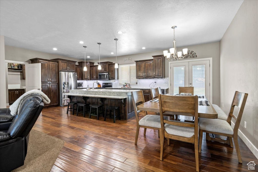Dining area with a chandelier, dark wood finished floors, and recessed lighting