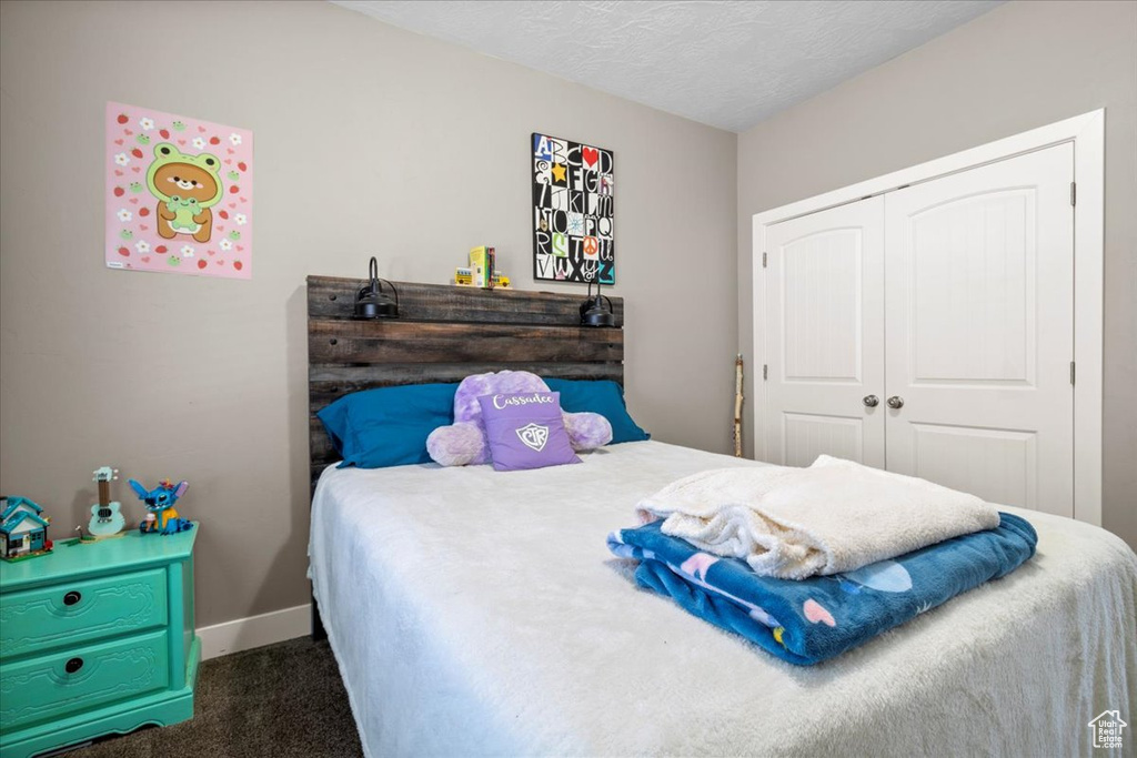 Bedroom with carpet floors, a closet, and a textured ceiling