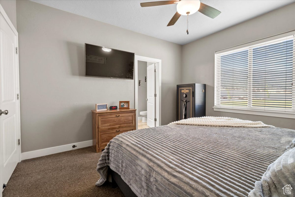 Carpeted bedroom featuring connected bathroom and a ceiling fan