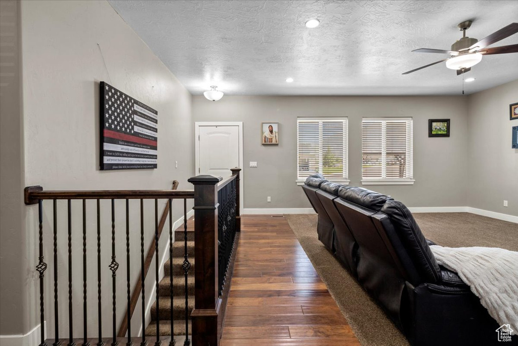 Living room with dark wood-type flooring, a ceiling fan, a textured ceiling, and recessed lighting