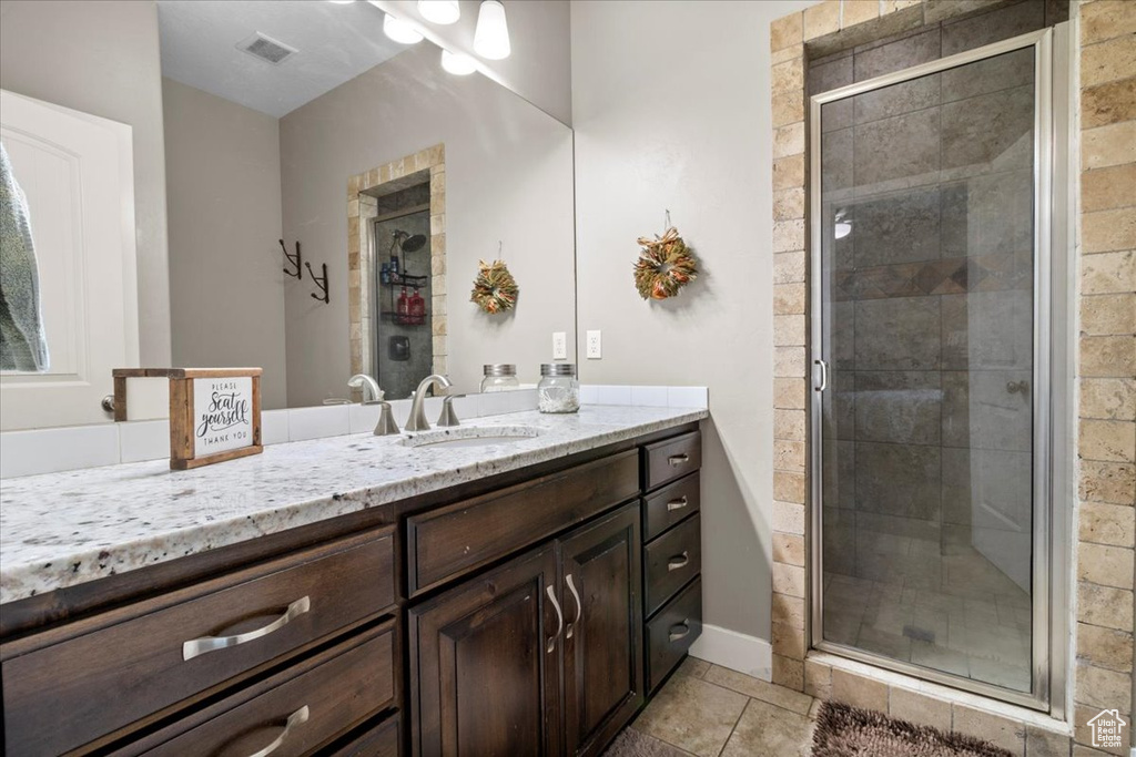 Full bath featuring vanity, a stall shower, and tile patterned floors