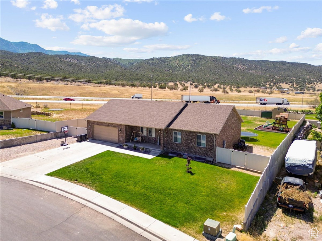 View of front of house with brick siding, a garage, a mountain view, and a fenced backyard