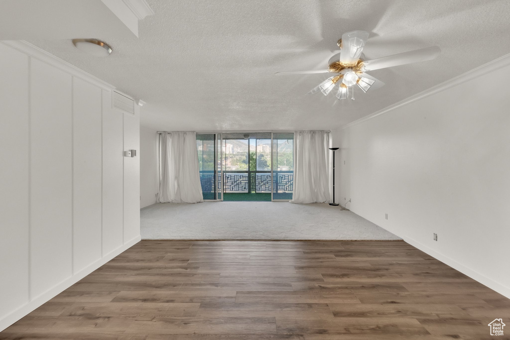 Empty room with a ceiling fan, a textured ceiling, and wood finished floors