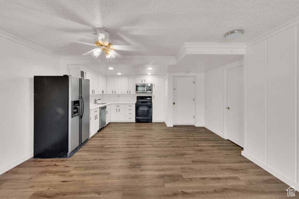 Kitchen with appliances with stainless steel finishes, crown molding, a ceiling fan, light countertops, and white cabinetry