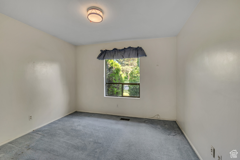 Carpeted spare room featuring baseboards
