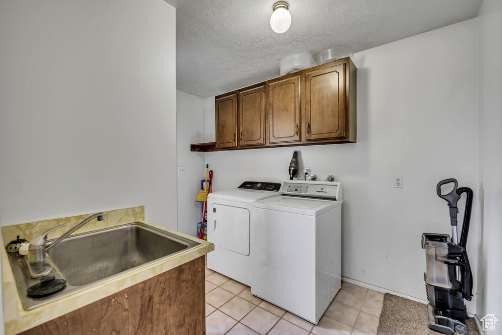 Laundry room featuring cabinet space, separate washer and dryer, light tile patterned flooring, and a textured ceiling