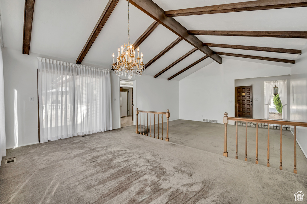 Unfurnished living room with a chandelier and carpet