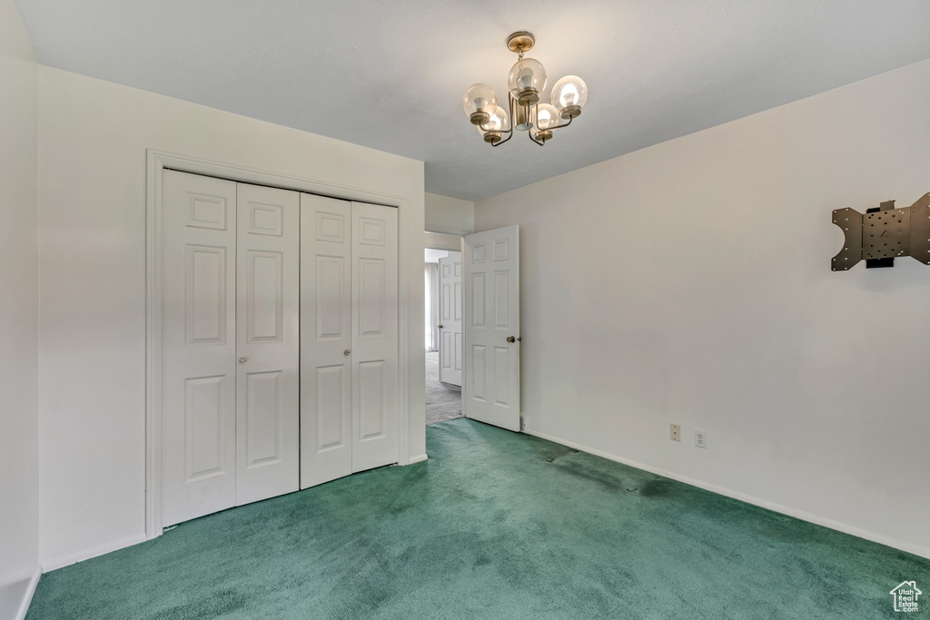 Unfurnished bedroom featuring carpet flooring, a chandelier, and a closet