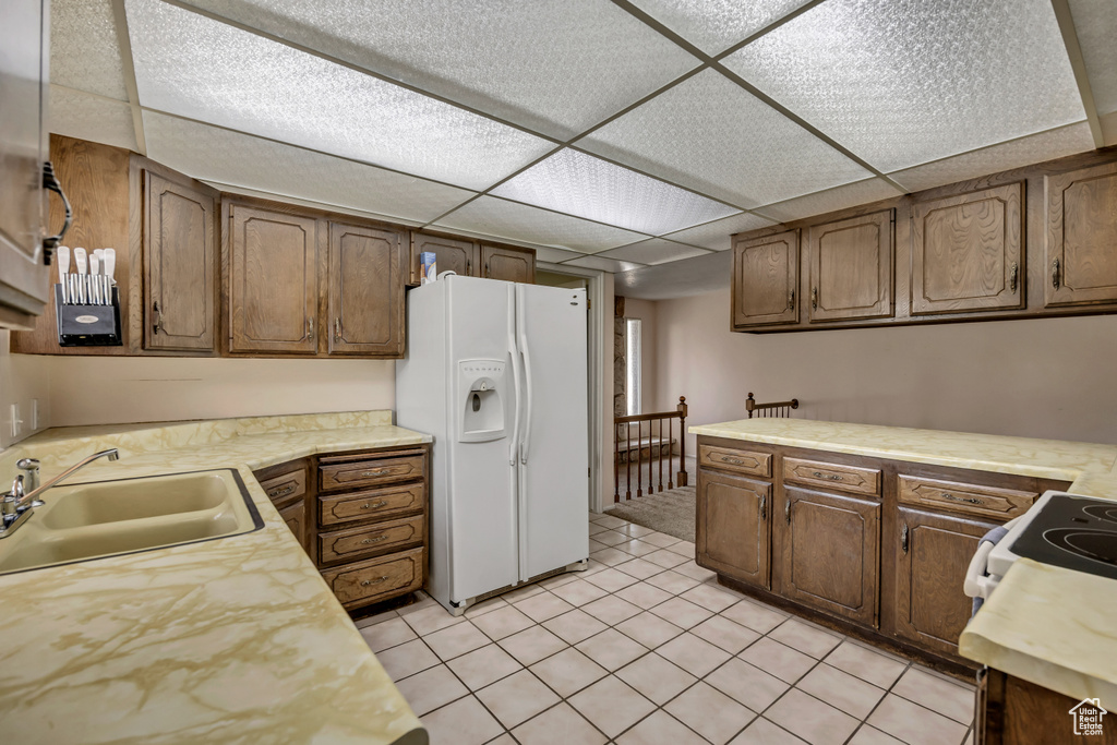 Kitchen featuring white refrigerator with ice dispenser, light countertops, and light tile patterned floors