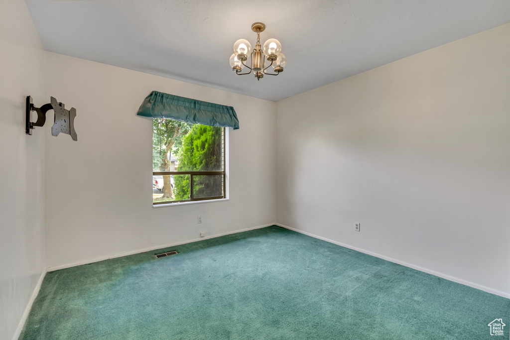 Spare room with a chandelier and carpet