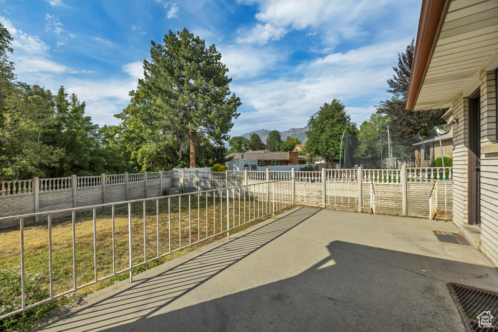 Fenced backyard featuring a trampoline, a patio area, and a mountain view