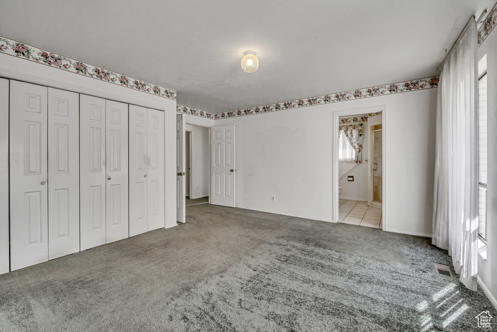 Unfurnished bedroom featuring carpet, a closet, and ensuite bath