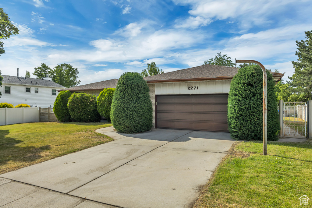 View of front facade with concrete driveway, a garage, board and batten siding, a gate, and roof with shingles