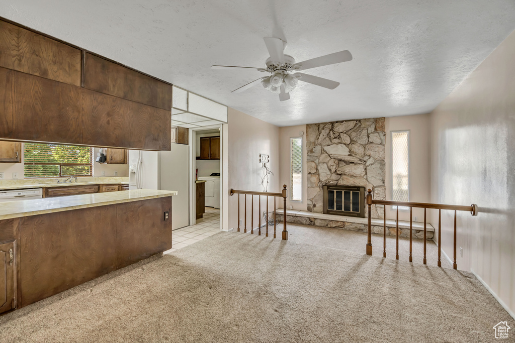 Kitchen featuring a ceiling fan, light countertops, light colored carpet, washer / clothes dryer, and white appliances