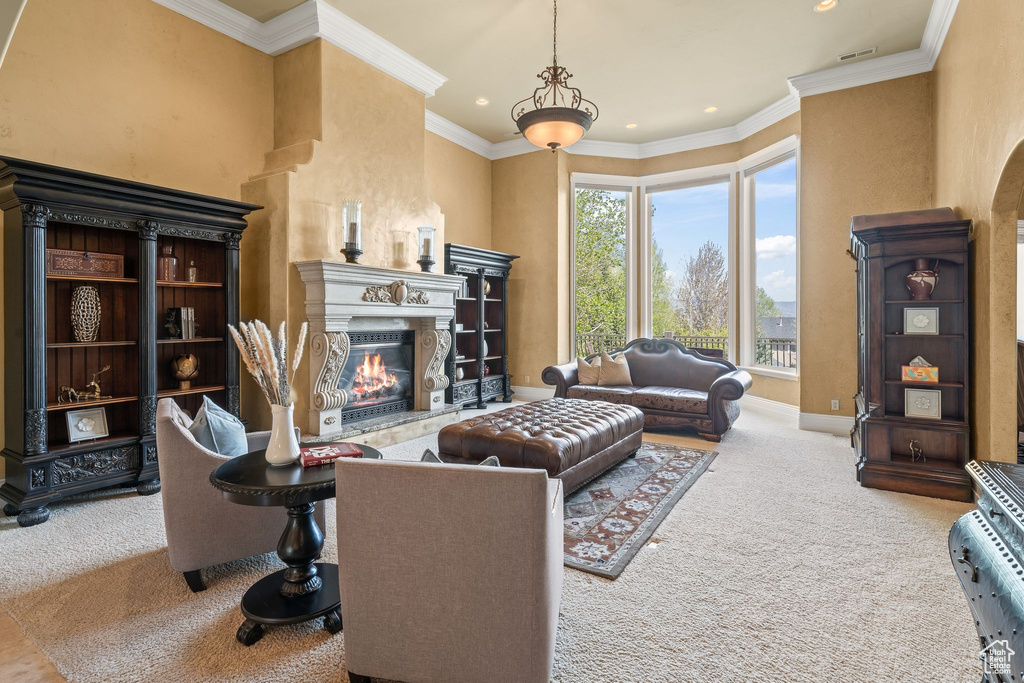 Carpeted living area featuring a high end fireplace, recessed lighting, ornamental molding, and arched walkways