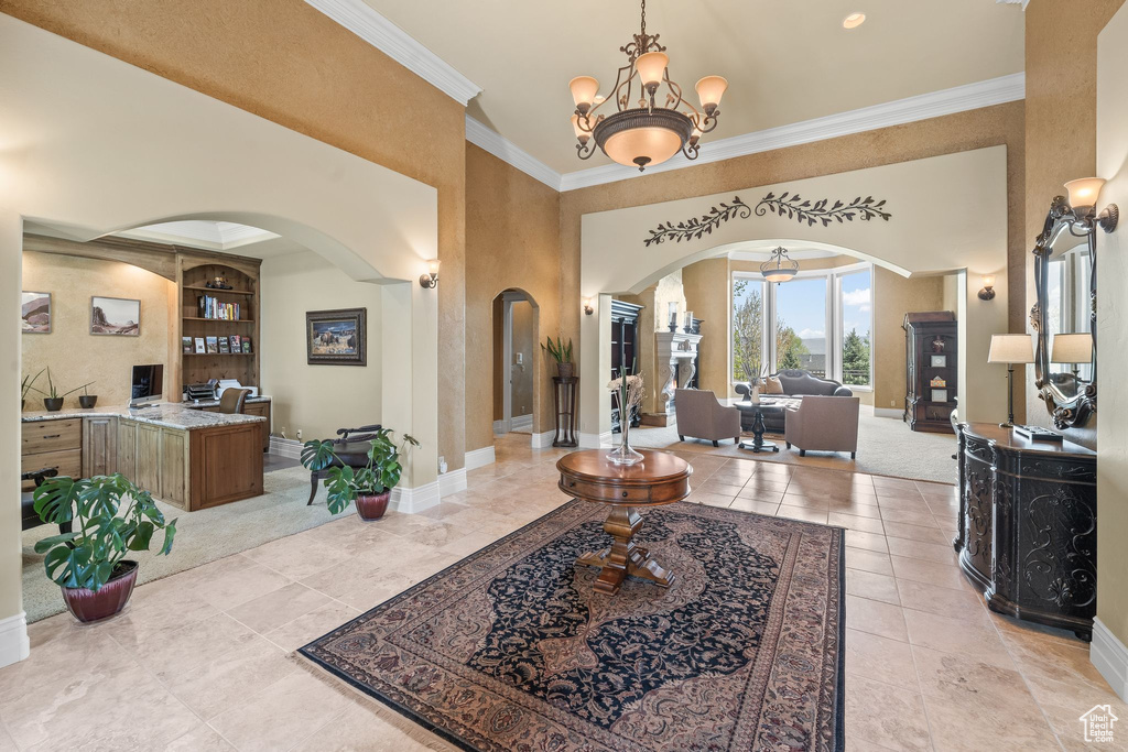 Entryway with arched walkways, ornamental molding, a chandelier, and light tile patterned floors
