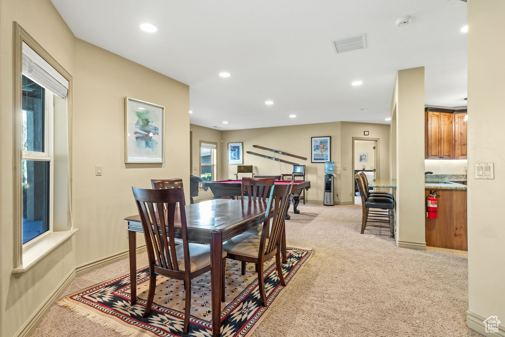 Dining area with light colored carpet and recessed lighting