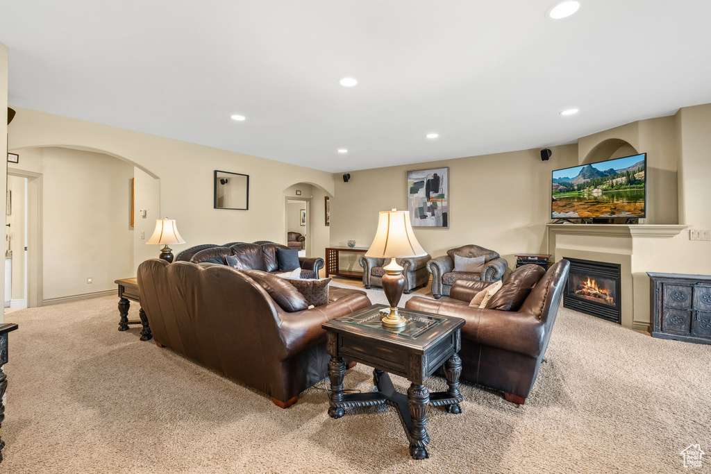Living room with arched walkways, carpet, recessed lighting, and a glass covered fireplace