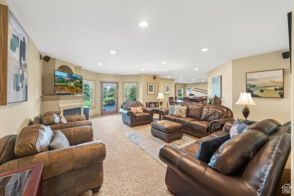 Living room featuring light colored carpet, recessed lighting, and a glass covered fireplace