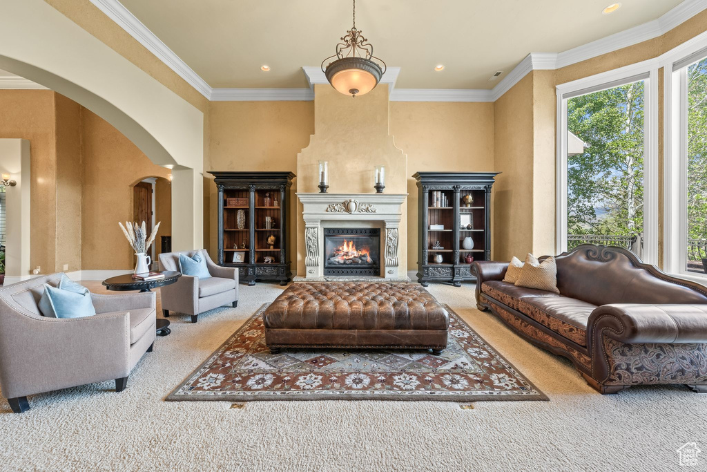 Carpeted living area with arched walkways, ornamental molding, a large fireplace, and recessed lighting