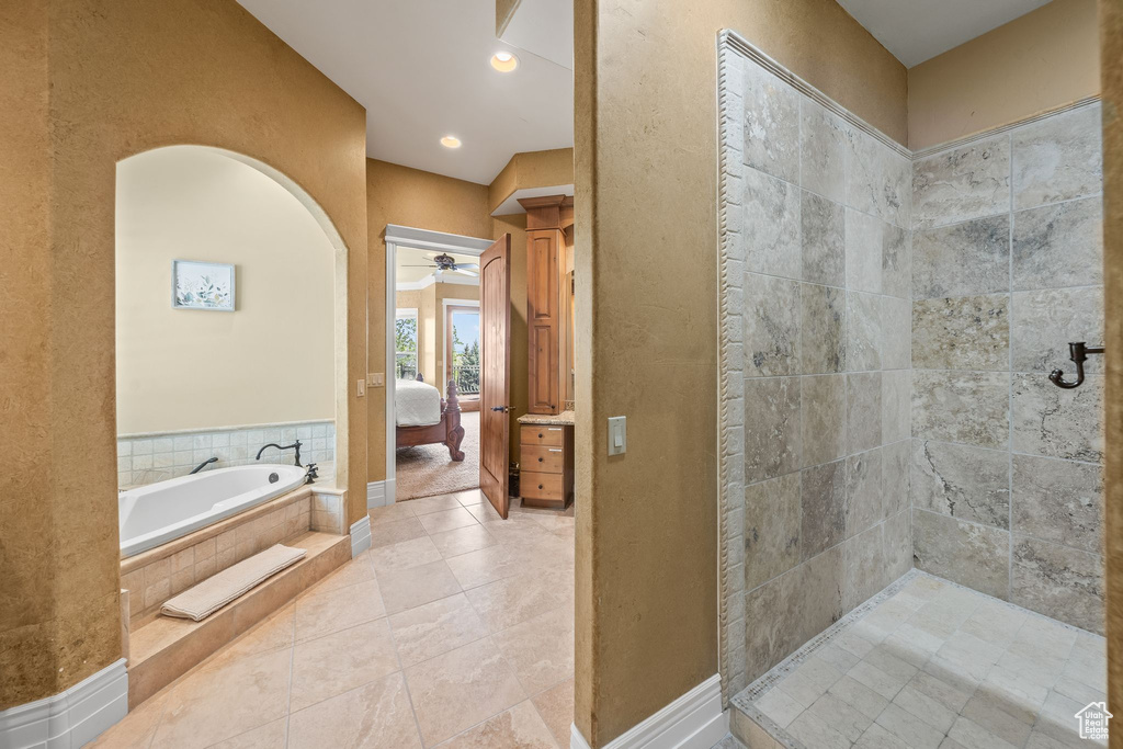Bathroom with connected bathroom, a ceiling fan, a garden tub, a textured wall, and tile patterned flooring