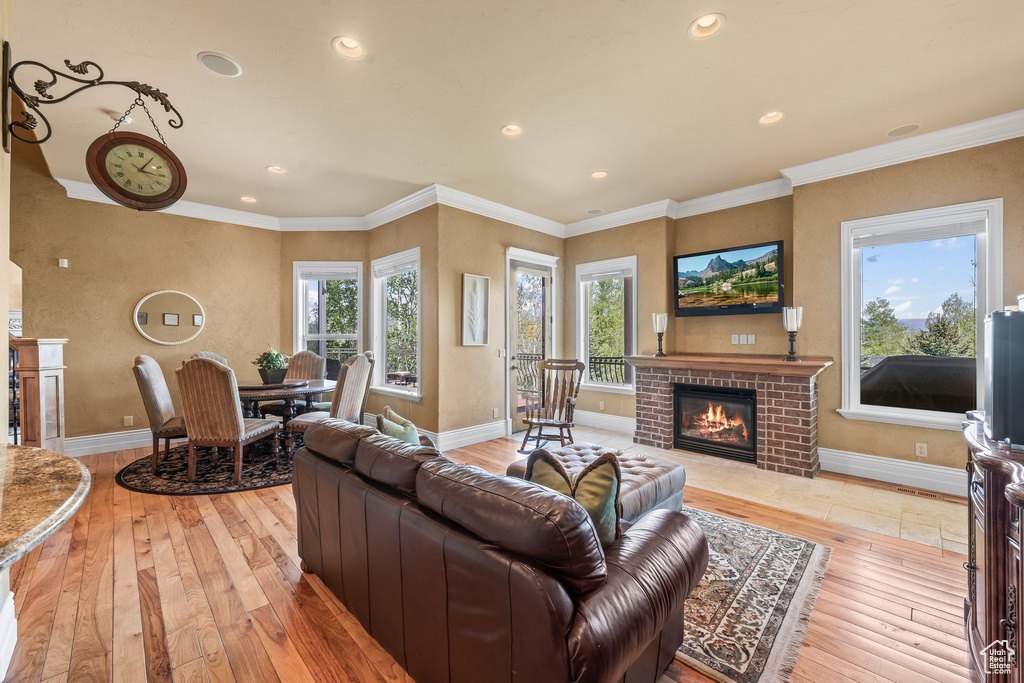 Living room featuring light wood-style floors, a brick fireplace, recessed lighting, and ornamental molding
