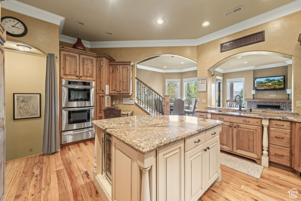 Kitchen with arched walkways, double oven, a warming drawer, light wood-type flooring, and recessed lighting