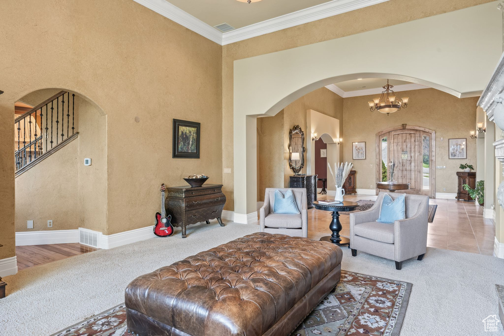 Carpeted living area with arched walkways, a towering ceiling, and crown molding