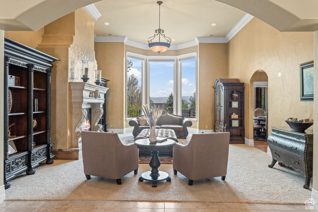 Living room featuring arched walkways, crown molding, a lit fireplace, recessed lighting, and tile patterned floors