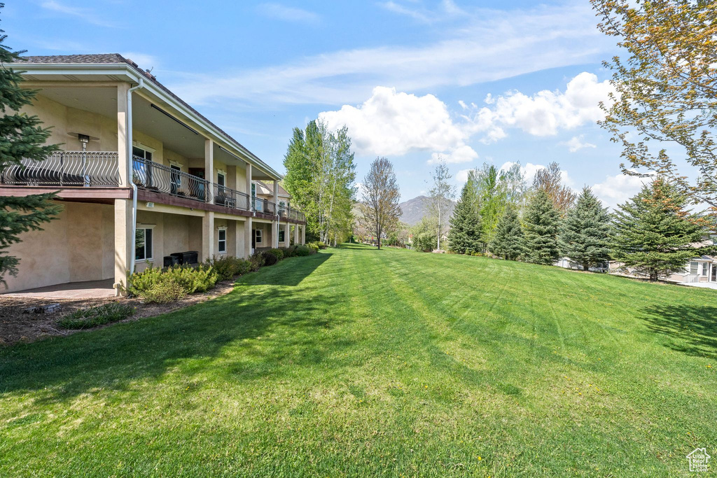 View of green lawn featuring a balcony
