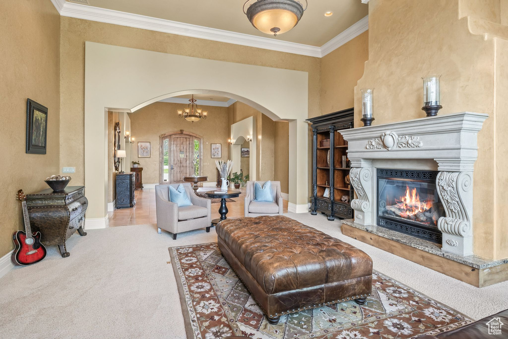 Carpeted living room with arched walkways, ornamental molding, a glass covered fireplace, and a chandelier