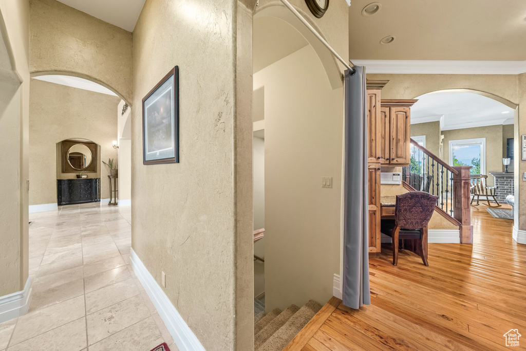 Corridor featuring arched walkways, ornamental molding, a textured wall, and stairway