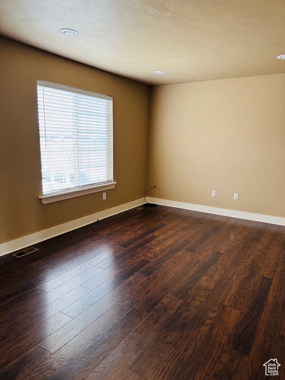 Empty room with dark wood-style floors and recessed lighting
