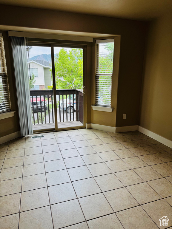 Unfurnished room with light tile patterned flooring and baseboards