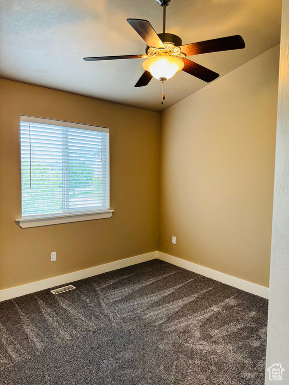 Spare room with dark colored carpet and a ceiling fan